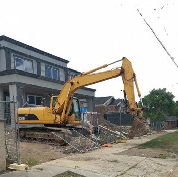 Excavator beside a damaged footpath, flagged for attention