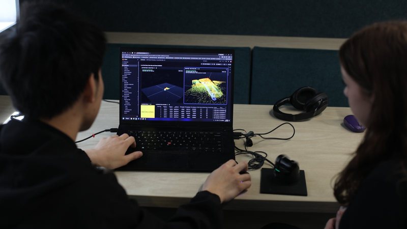 Two team members reviewing a live LiDAR point cloud on a laptop