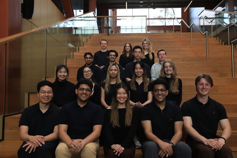 The VISTA team seated together on timber stairs